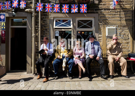 Haworth, West Yorkshire, UK. 17th May 2014. Locals and visitors outside a local pub. Haworth, a small village in the city of Bradford in West Yorkshire has held the first day of its 1940s weekend on Saturday, March 17, 2014. Good weather brought hundreds into the village for this event where locals and visitors don wartime attire. Credit:  Christopher Middleton/Alamy Live News Foto Stock