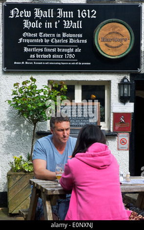 Giovane seduto fuori il foro t' pub a parete, Bowness, Parco Nazionale del Distretto dei Laghi, Cumbria, England Regno Unito Foto Stock