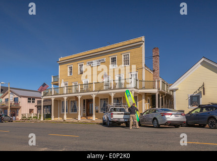 Mendocino Hotel, mendocino, Mendocino County, California. Un uomo manouevres una tavola da surf da un carrello di prelievo. Foto Stock