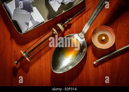 La preparazione di eroina con un cucchiaio, una siringa e una candela su un tavolo Foto Stock
