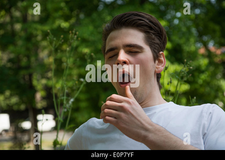 Bel giovane uomo che soffre di hayfever allergia starnuti in posizione di parcheggio Foto Stock