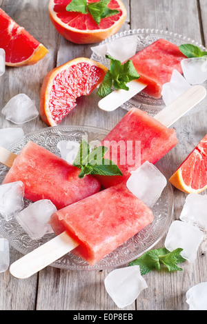 Pompelmo rosso popsicles fatti in casa con cubetti di ghiaccio. Messa a fuoco selettiva. Foto Stock