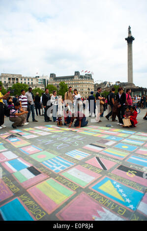 Londra, Regno Unito. Il 17 maggio 2014. Uomo in Trafalgar Square disegno tutte le bandiere del mondo. Le persone potrebbero lasciare alcune monete sulla bandiera del loro paese. I turisti e i londinesi si erano radunati tutti intorno mentre l'uomo è stato credito di disegno: Giulia Fiori/Alamy Live News Foto Stock