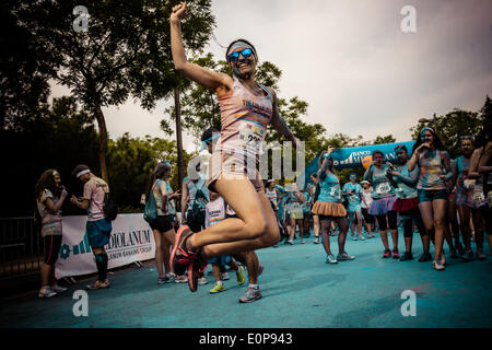 Barcellona, Spagna. 18 maggio 2014: un runner salta come il suo amico prende una foto della sua durante il 5km colour run in Barcellona Credito: matthi/Alamy Live News Foto Stock