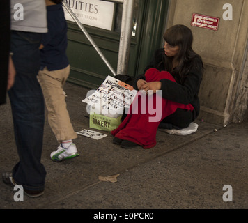 Donna senzatetto raggiungere fuori per la guida su strada in midtown Manhattan, NYC Foto Stock