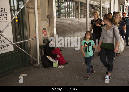 Donna senzatetto raggiungere fuori per la guida su strada in midtown Manhattan, NYC Foto Stock