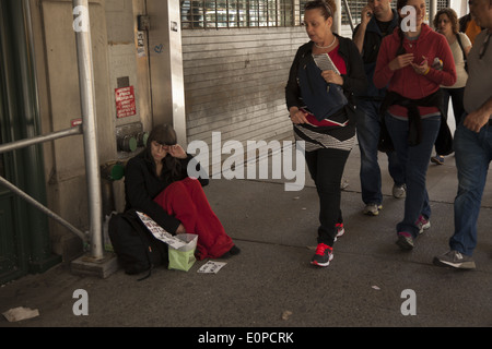 Donna senzatetto raggiungere fuori per la guida su strada in midtown Manhattan, NYC Foto Stock