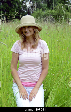 Donna con cappello seduti sul prato Foto Stock