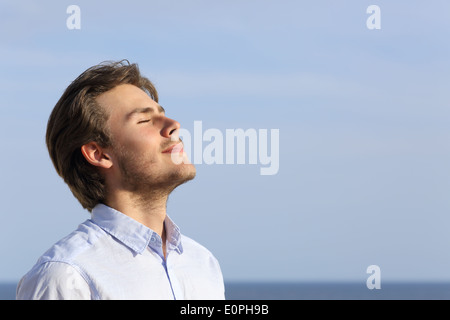 Felice giovane uomo respirazione profonda con l'orizzonte in background Foto Stock