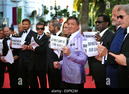 (140518) -- CANNES, 18 maggio 2014 (Xinhua) -- Cast di 'Le parti soggette a usura 3', mantenendo i banner fino a leggere 'riportare le nostre ragazze", parte di una campagna per la liberazione dei rapiti studentesse nigeriano essendo tenuto dalla Nigerian gruppo estremista islamico Boko Haram, come essi arrivano al red carpet per lo screening di 'L'Homesman' alla 67th Cannes Film Festival di Cannes, Francia meridionale, il 18 maggio 2014. (Xinhua/Chen Xiaowei) Foto Stock