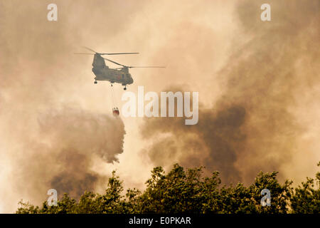 Un US Marine Corps elicottero porta acqua in un Bambi Bucket a contribuire alla lotta contro il tomahawk e Las Pulgas incendi che bruciano le colline pedemontane Maggio 16, 2014 intorno a Camp Pendleton, California. Le evacuazioni forzate oltre 13.000 persone dalle loro case come il fuoco bruciavano attraverso San Diego County. Foto Stock