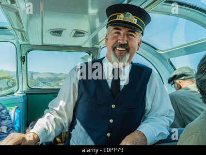 Il conduttore del treno sorrisi come egli si trova rivolta in avanti nell'osservazione vintage treno auto. Foto Stock