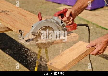 Impresa edile lavoratore utilizzando tenuto in mano unità worm sega circolare per il taglio di pannelli su una nuova home progetti di costruzione Foto Stock