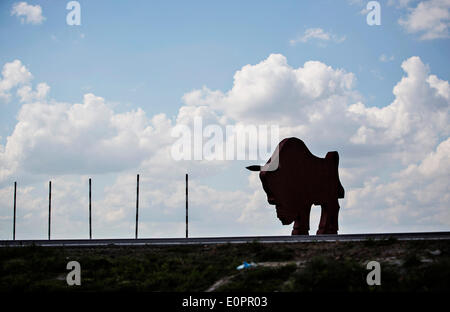 Un SUV con i giornalisti scorre attraverso un campo per visualizzare una gigantesca statua di bielorusso simbolo nazionale, il Bisonte Europeo, su una autostrada che conduce a Minsk, Bielorussia, Sabato, Maggio 10th, 2014. Le autostrade in Bielorussia non conformi con West norme europee. Western Foto Stock