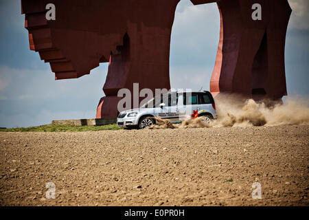 Un SUV con i giornalisti scorre attraverso un campo per visualizzare una gigantesca statua di bielorusso simbolo nazionale, il Bisonte Europeo, su una autostrada che conduce a Minsk, Bielorussia, Sabato, Maggio 10th, 2014. Le autostrade in Bielorussia non conformi con West norme europee. Western Foto Stock
