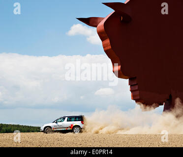 Un SUV con i giornalisti scorre attraverso un campo per visualizzare una gigantesca statua di bielorusso simbolo nazionale, il Bisonte Europeo, su una autostrada che conduce a Minsk, Bielorussia, Sabato, Maggio 10th, 2014. Le autostrade in Bielorussia non conformi con West norme europee. Western Foto Stock
