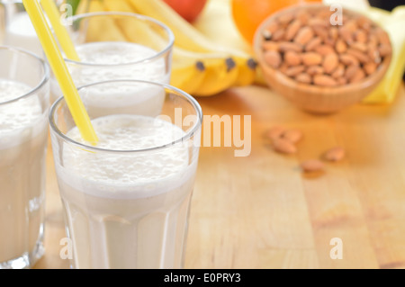 Banana e mandorla frullato di latte in un bicchiere su un tavolo da cucina. Bevanda estiva fatta di banana, latte di mandorla e pochi dactyl. Foto Stock