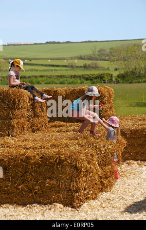 Tre giovani ragazze che giocano su paglia balle di fieno a Abbotsbury, DORSET REGNO UNITO su una calda giornata di sole di maggio Foto Stock