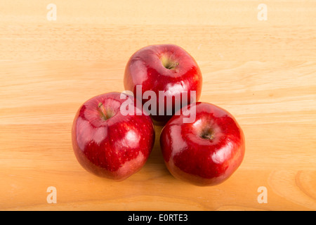 Tre mature mele rosse su una tavola di legno Foto Stock