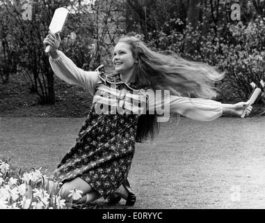 L'attrice Fiona Fullerton spazzolare i capelli in giardino Foto Stock