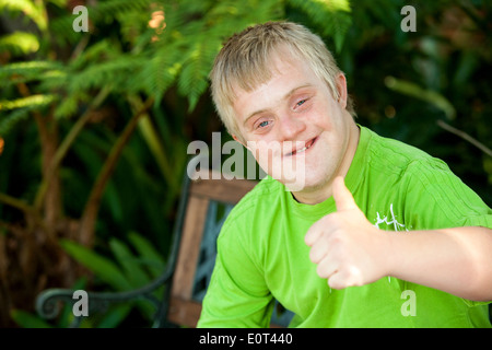 Close up ritratto di carino ragazzo disabile che mostra i pollici fino all'esterno. Foto Stock