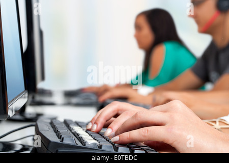 Macro close up di mani femminili digitando sulla tastiera del computer in ufficio. Foto Stock