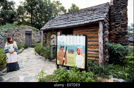 Una guida attende mentre due visitatori pongono dietro la foto ritagliata a segno i giovani pionieri cabina a Ozark Centro Folk, un parco statale in Arkansas, STATI UNITI D'AMERICA Foto Stock