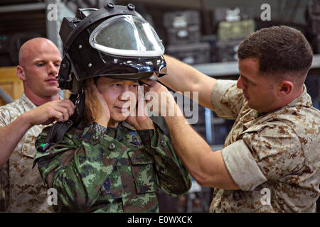 Due Marines americani aiuto Royal Thai Forze Armate Lt. Gen. Krisda Norapoompipat mettere sul casco da un avanzato tuta bomba durante una visita a Camp Hansen 19 Maggio 2014 a Okinawa, Giappone. La visita ha avuto luogo nello stesso tempo il Thai militare ha annunciato la legge marziale per sedare la protesta di interrompere la nazione. Foto Stock