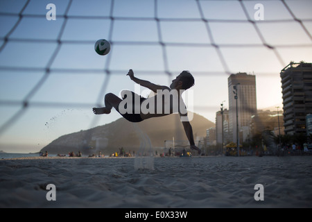 Un calciatore acrobatically segna un gol da un overhead bicyclette calcio calcio sulla spiaggia di Ipanema a Rio de Janeiro in Brasile Foto Stock