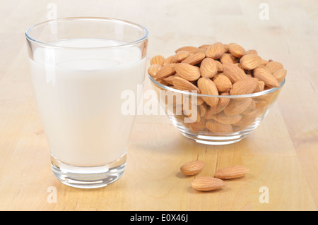 Latte di Mandorla come un sostituto per il latte fresco. Un bicchiere di latte di mandorla e la tazza di mandorle su un tavolo di legno. Foto Stock