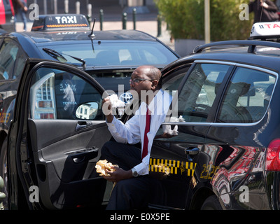 Taxi driver avente il pranzo e mangiare panino in attesa nel suo posto macchina Lussemburgo Bruxelles Belgio Foto Stock