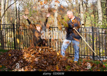 Uomo e donna che gioca in foglie di autunno Foto Stock