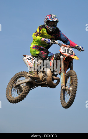 Il Motocross è una forma di moto racing tenutasi il ruvido racchiuso off-road circuiti. Moto rider sulla bici scramble, salto in alto nel cielo blu Foto Stock