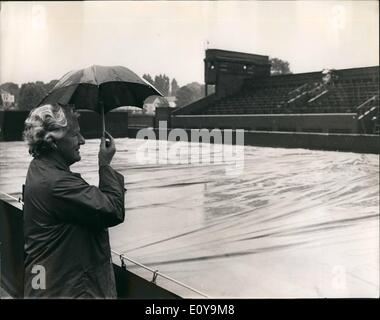 Giugno 06, 1969 - La pioggia può contenere fino gioca sul primo giorno del torneo di Wimbledon Open Championship: Immagine mostra: RA M. Clark ripari sotto in piccolo ombrello mentre in attesa sotto la pioggia sperando che il gioco finirà per iniziare. Foto Stock