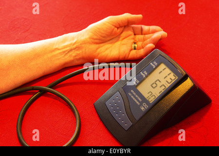 Visualizzazione della misurazione della pressione sanguigna effettuata a casa su una tabella rossa Foto Stock