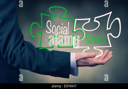 Un imprenditore tenendo in una rete sociale il concetto di puzzle. Foto Stock