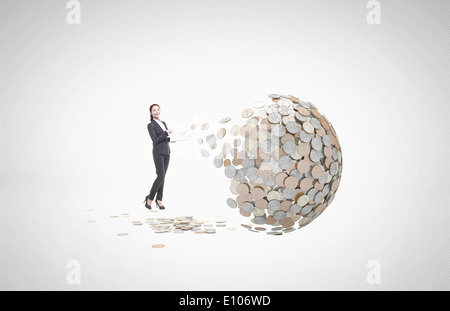 Un business donna in piedi accanto a una sfera di monete Foto Stock