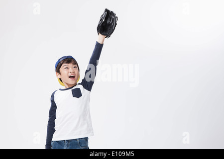 Un giovane ragazzo di raggiungere elevate con un guanto da baseball Foto Stock