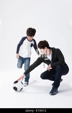 Un padre e un figlio a giocare con un pallone da calcio Foto Stock