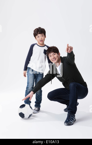 Un padre e un figlio a giocare con un pallone da calcio Foto Stock