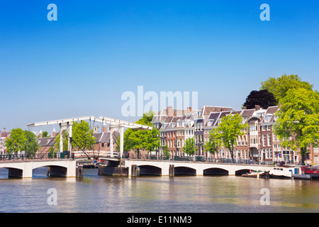 Il Magere Brug ('Skinny ponte") di Amsterdam lungo il fiume Amstel su una bella giornata di sole Foto Stock