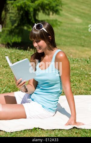 Lug. 12, 2010 - Luglio 12, 2010 - sorridente giovane donna leggere il libro nel parco sulla giornata di sole seduti su una coperta Ã Â© CTK/ZU Foto Stock