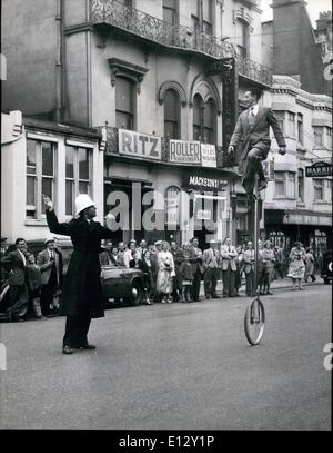 Febbraio 26, 2012 - nessun problema di traffico qui; traffico di Brighton poliziotto appare piuttosto indifferenti come una ruota ciclista Banner trundles Forbutt giù per la strada. Banner Forbutt il lavoro è sempre in equilibrio; in sella a un ciclo di ruota ha bisogno di un bel senso di equilibrio, tenendosi otto piedi da terra, fino una esile albero montato su di una singola ruota, è una costante fonte di divertimento per chi vede la Brighton il circo di ghiaccio e al cittadino locale che sono ormai abituati a vederlo fare il suo modo per e dal teatro il suo strano veicolo Foto Stock