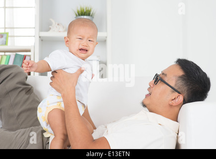 Famiglia asiatica stile di vita a casa. Padre consolante di piangere baby boy. Foto Stock