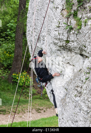 Uomo di arrampicata parete rocciosa. Foto Stock