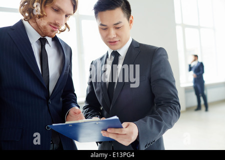 I giovani imprenditori a discutere di piano o di carta alla riunione in ufficio Foto Stock