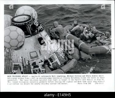 Apr. 17, 2012 - Luna viaggiatori a galla -- Apollo-11 astronauti Neil Armstrong, Michael Collins e Edwin Aldrin attendono elicottero pick-up da una zattera come tenente pararescueman Clancey Hatleberg chiude il portello sulla loro navicella spaziale. Il lunar viaggiatori schizzato in basso a destra sul target nel Pacifico nei pressi di Hawaii su luglio 24. Essi indossato biologici indumenti di isolamento prima di lasciare la capsula e indossavano i loro fino a quando non è entrato una quarantena van a bordo del recupero nelle vicinanze carrier USS Hornet. Foto Stock