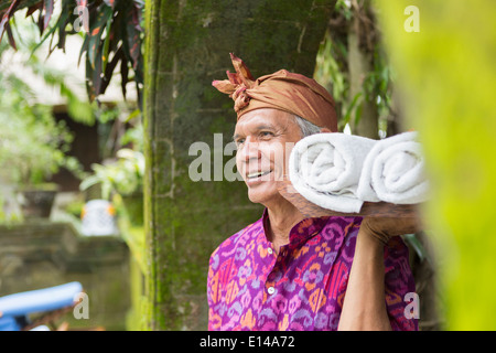 Lavoratore Balinese che porta asciugamani laminato Foto Stock