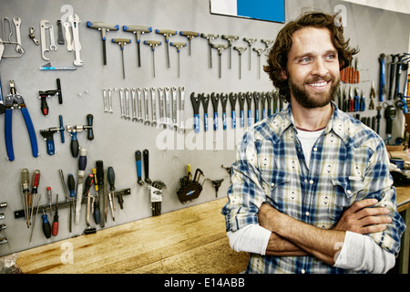 Uomo caucasico sorridente in negozio di riparazione di biciclette Foto Stock