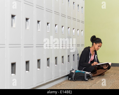 Studente nero lettura nella parte anteriore di armadietti Foto Stock